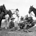 Five Cowboys playing and singing to their horses